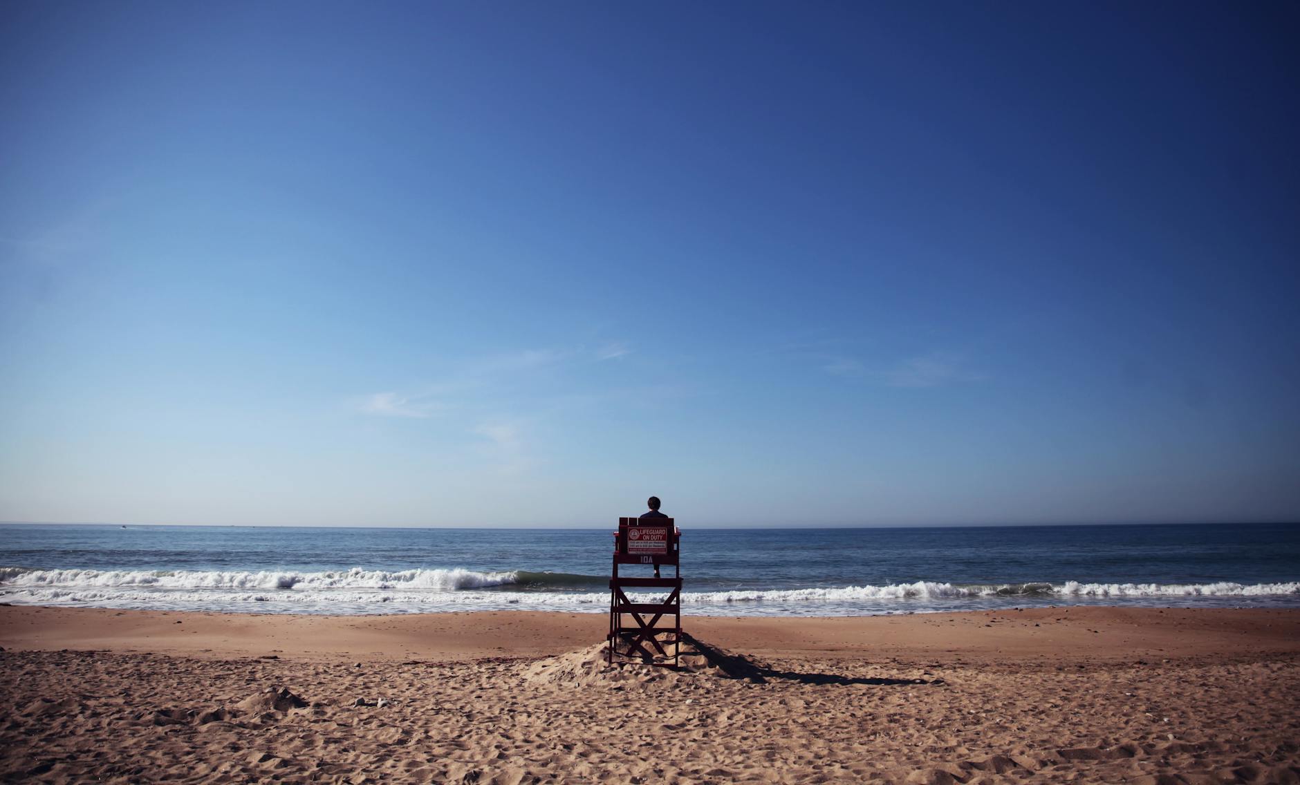 photo of person sitting on lifeguard tower