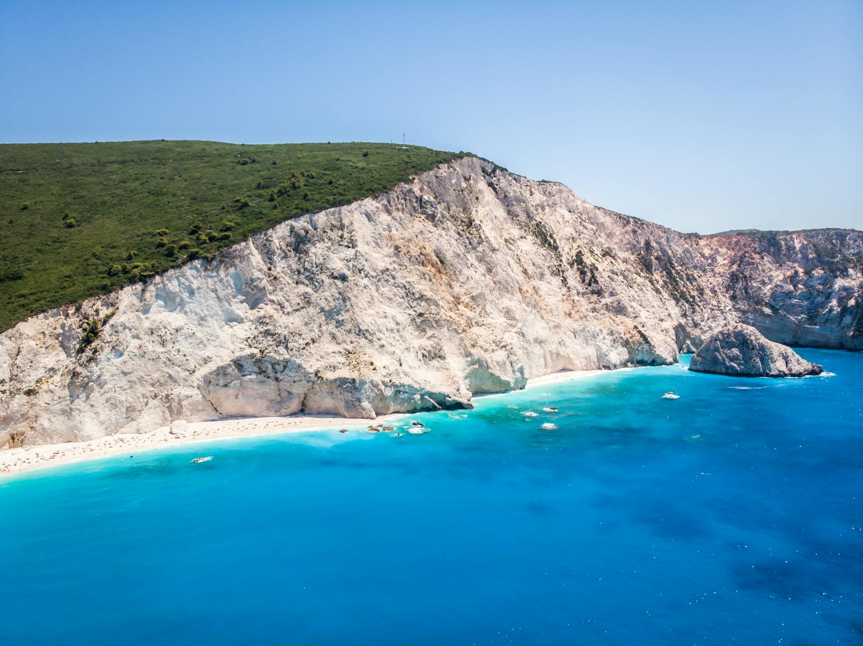 picturesque turquoise sea washing sandy beach surrounded by white rocky cliff