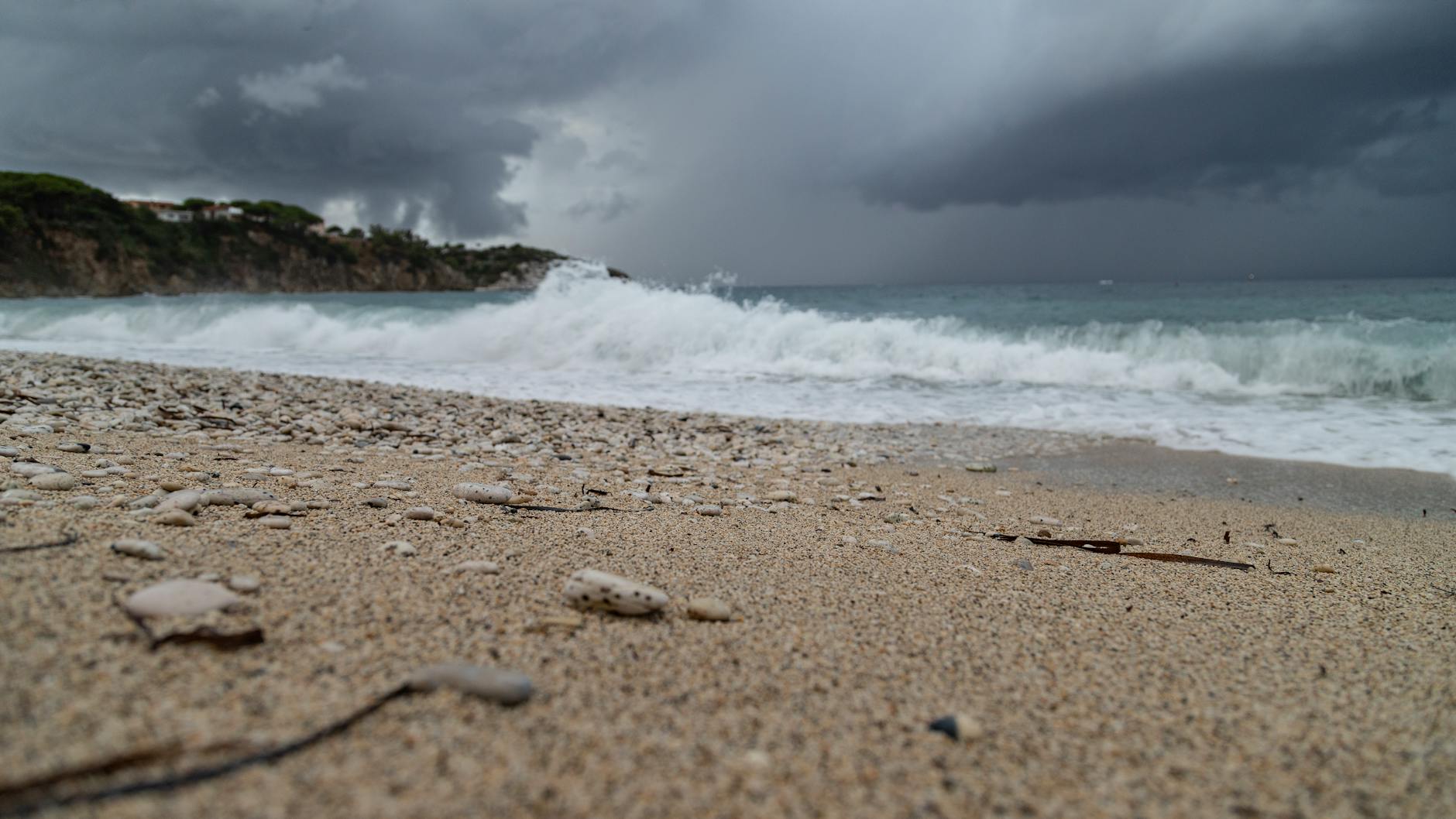 a beach with waves crashing on the shore and a stormy sky