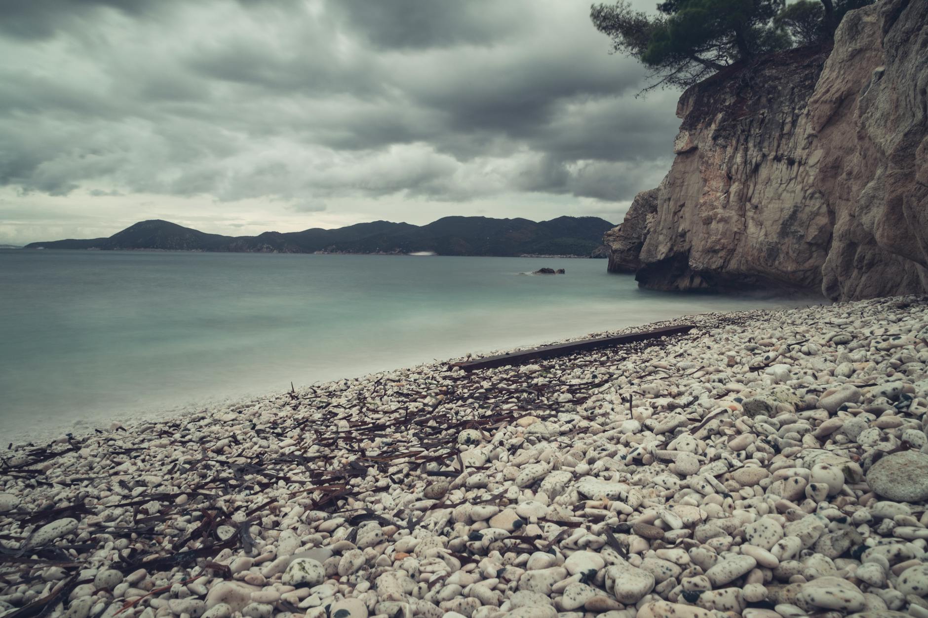 a beach with rocks and water under a cloudy sky